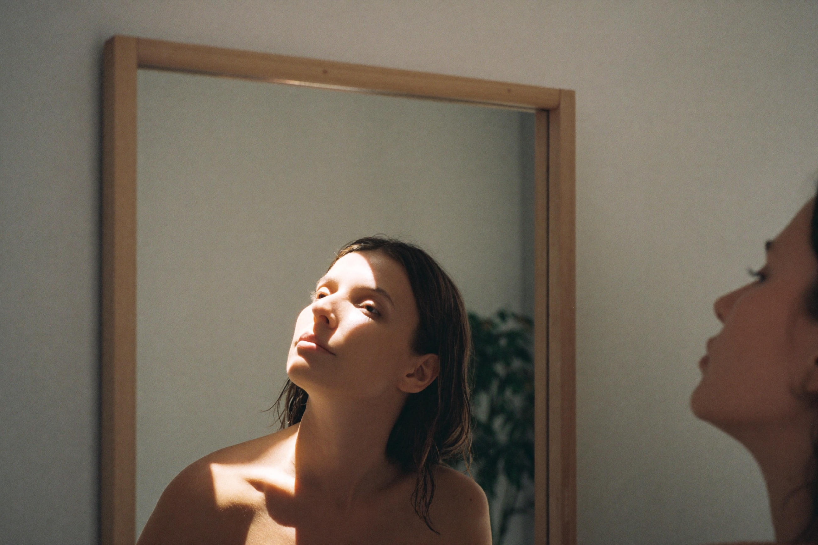 Woman studying her own face in a mirror in warm natural light